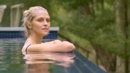 Testimonial Video. Blonde woman in an outdoor pool looking towards the horizon